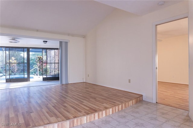 empty room with light wood-style flooring and vaulted ceiling