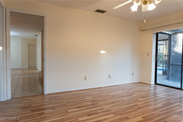 empty room with light wood finished floors, ceiling fan, visible vents, and baseboards