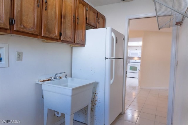 kitchen with a sink, white appliances, brown cabinetry, and light countertops