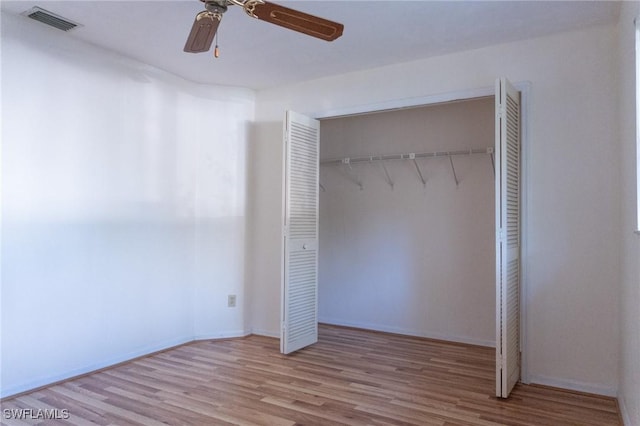 unfurnished bedroom featuring a closet, wood finished floors, visible vents, and a ceiling fan