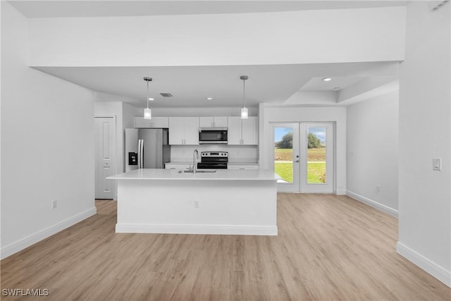 kitchen featuring hanging light fixtures, appliances with stainless steel finishes, light countertops, and a kitchen island with sink