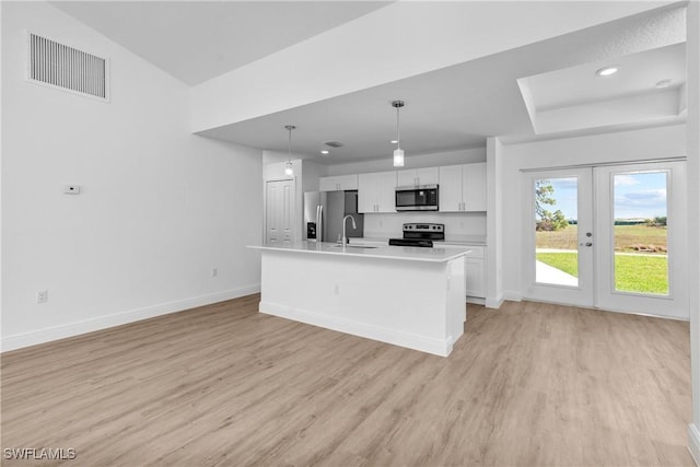 kitchen with a center island with sink, visible vents, appliances with stainless steel finishes, light countertops, and pendant lighting