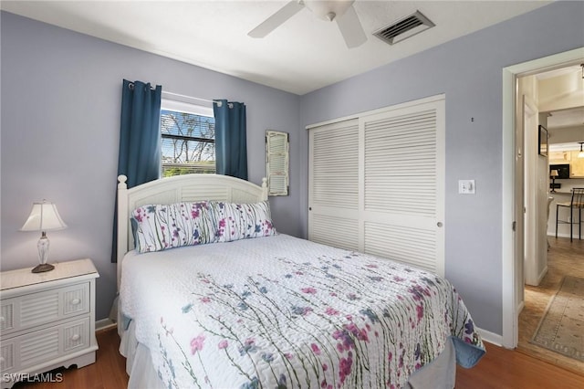 bedroom with a closet, visible vents, baseboards, and wood finished floors