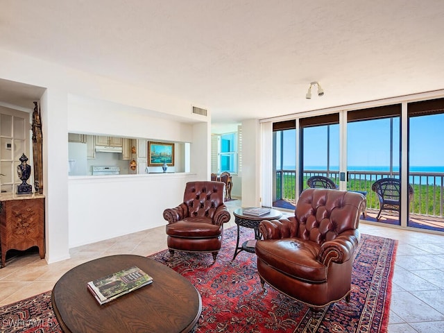 living room with a water view, light tile patterned floors, expansive windows, and visible vents