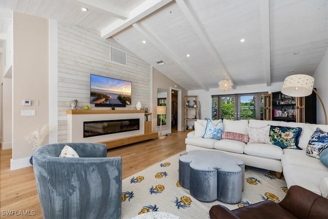 living area featuring a glass covered fireplace, visible vents, lofted ceiling with beams, and wood finished floors