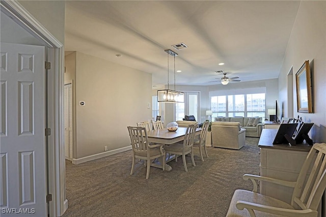 dining area featuring ceiling fan with notable chandelier, dark colored carpet, visible vents, and baseboards