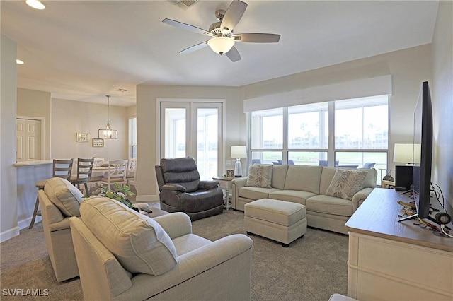 living room featuring a ceiling fan, light colored carpet, and baseboards