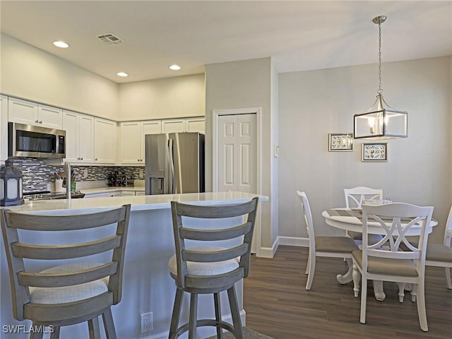 kitchen featuring stainless steel appliances, visible vents, white cabinets, light countertops, and decorative light fixtures