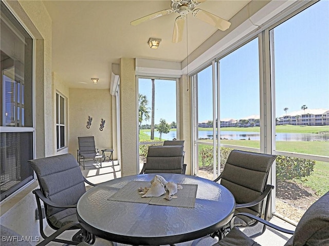 sunroom featuring a water view and a ceiling fan