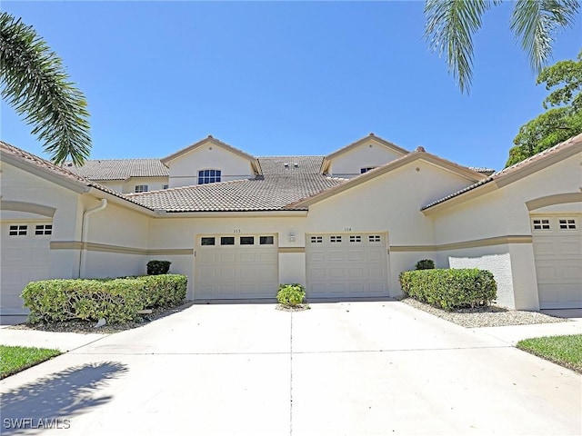 mediterranean / spanish home with driveway, a tiled roof, an attached garage, and stucco siding