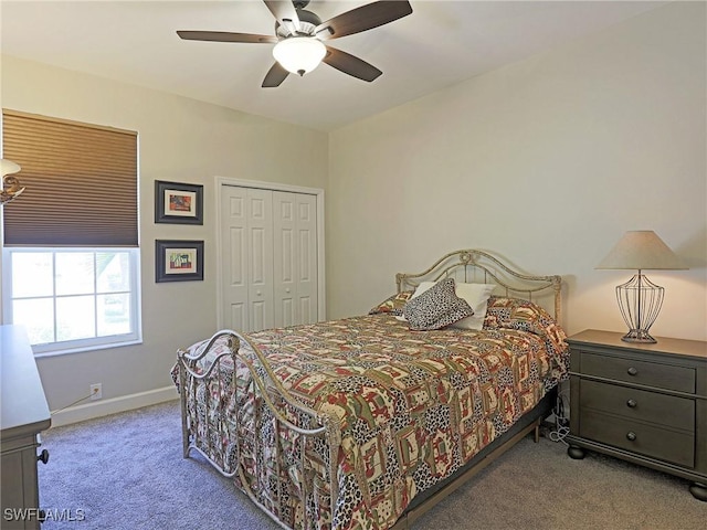 bedroom featuring light carpet, a closet, a ceiling fan, and baseboards