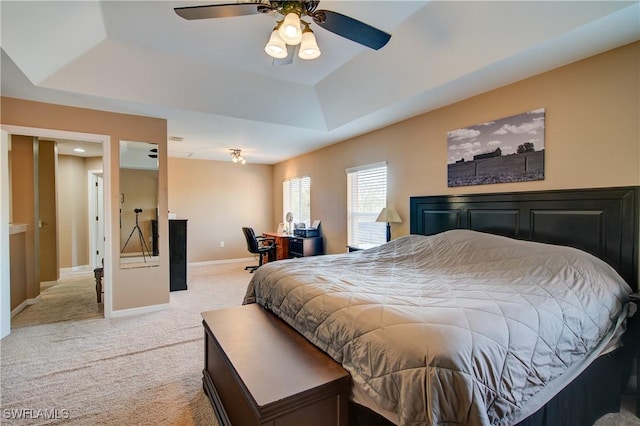 bedroom featuring a tray ceiling, light carpet, baseboards, and a ceiling fan