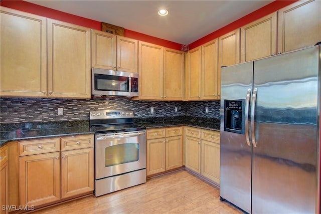 kitchen featuring light wood-type flooring, dark stone countertops, recessed lighting, appliances with stainless steel finishes, and decorative backsplash