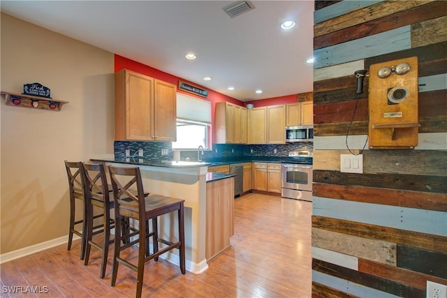 kitchen featuring visible vents, backsplash, light wood-style flooring, appliances with stainless steel finishes, and a sink