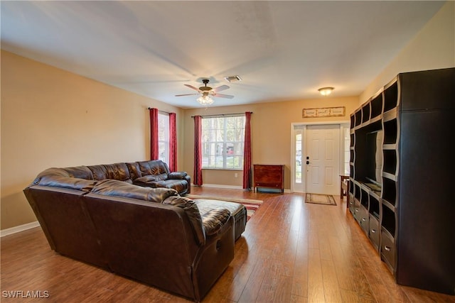 living room with visible vents, a ceiling fan, baseboards, and hardwood / wood-style flooring