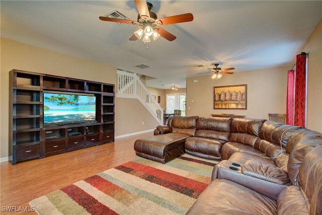 living area with stairway, baseboards, visible vents, and light wood-type flooring