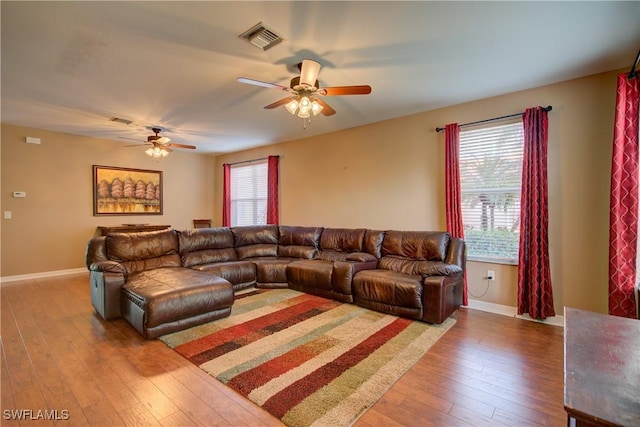 living room with hardwood / wood-style floors, baseboards, visible vents, and a wealth of natural light