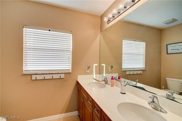 full bathroom with a sink, visible vents, toilet, and double vanity