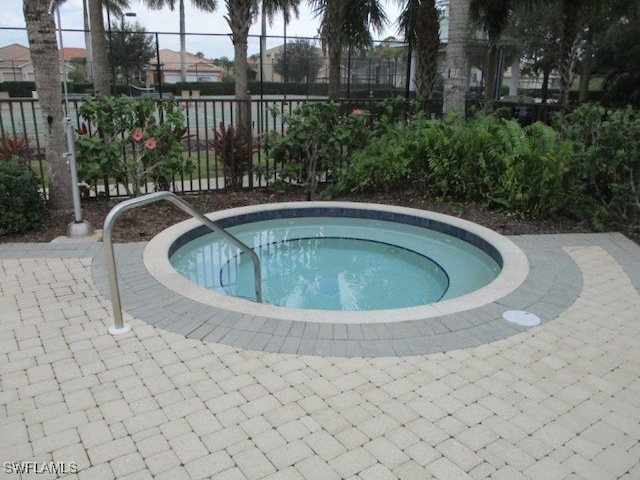 view of swimming pool with a community hot tub and fence