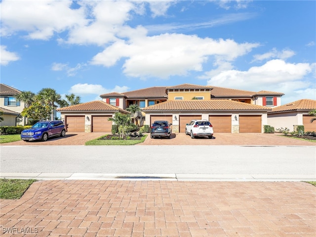 view of front facade featuring a garage, driveway, a tiled roof, and stucco siding