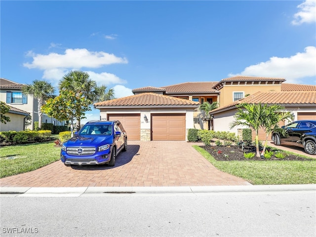 view of front of property featuring a garage, decorative driveway, a tile roof, and stucco siding