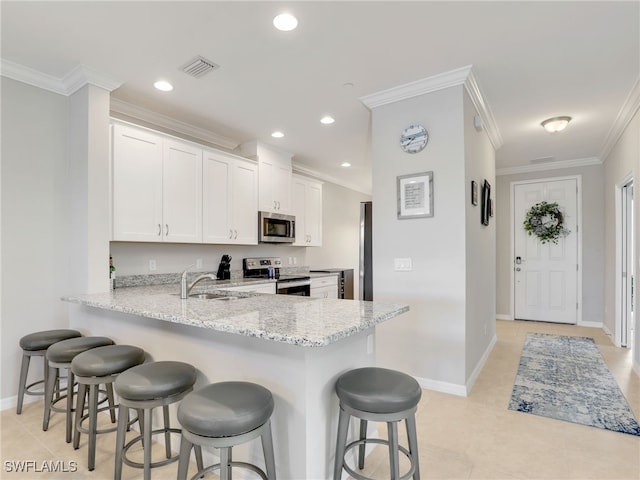 kitchen featuring light stone counters, stainless steel appliances, visible vents, ornamental molding, and a sink