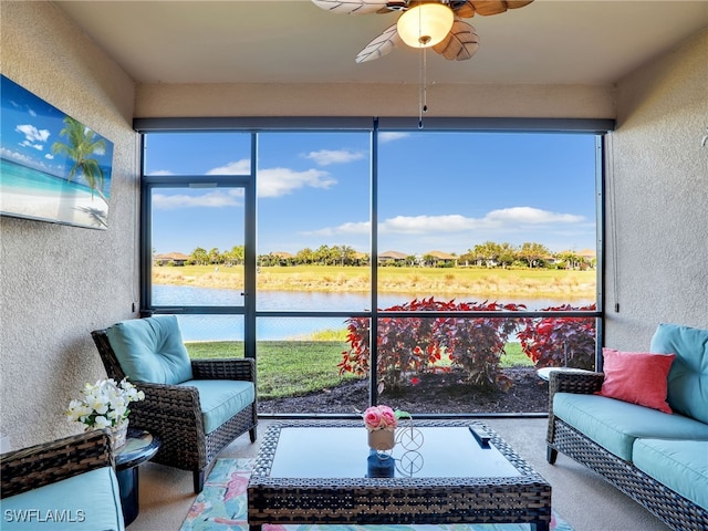 sunroom with ceiling fan and a water view