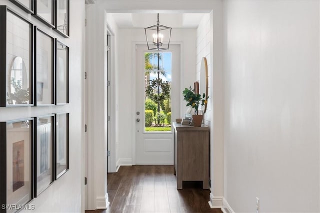 entryway featuring baseboards, dark wood finished floors, and a notable chandelier