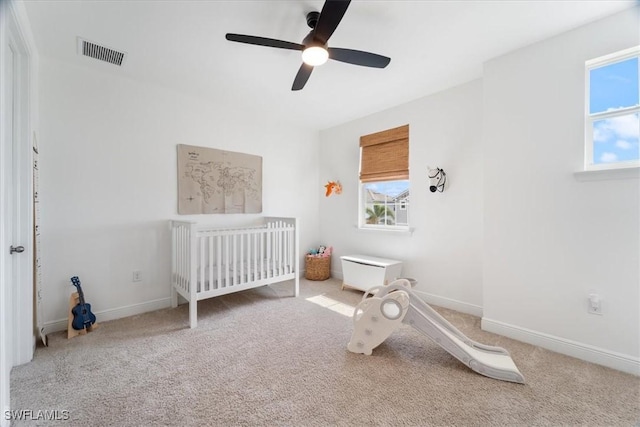 bedroom featuring a nursery area, visible vents, carpet flooring, and multiple windows