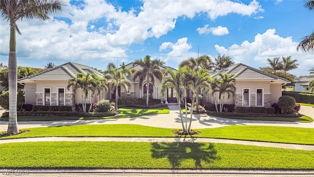 view of front of house featuring stone siding, stucco siding, a tiled roof, and a front yard