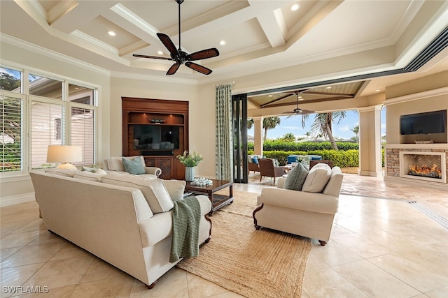 living room featuring coffered ceiling, a warm lit fireplace, ceiling fan, and ornamental molding