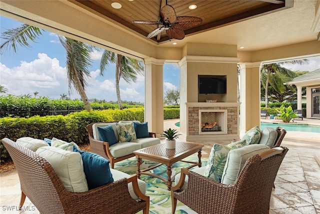 view of patio / terrace with a fenced in pool, fence, a ceiling fan, and an outdoor living space with a fireplace