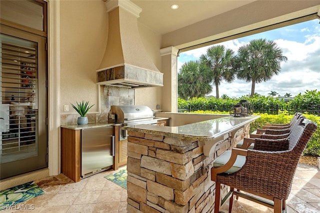 view of patio / terrace featuring outdoor wet bar, exterior kitchen, and a grill