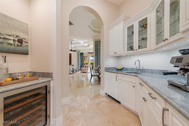 bar with baseboards, wine cooler, arched walkways, coffered ceiling, and a sink