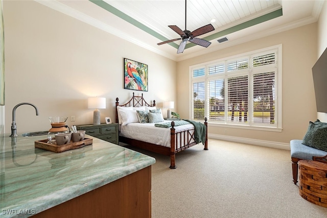 bedroom with a sink, a tray ceiling, crown molding, baseboards, and light colored carpet