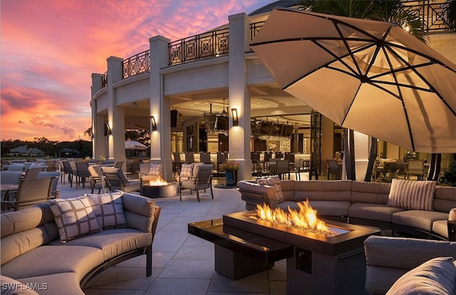 view of patio featuring an outdoor living space with a fire pit and a balcony