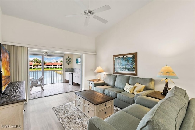 living area with high vaulted ceiling, light wood-style flooring, and a ceiling fan