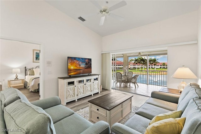 living room featuring light wood-style floors, visible vents, high vaulted ceiling, and a ceiling fan