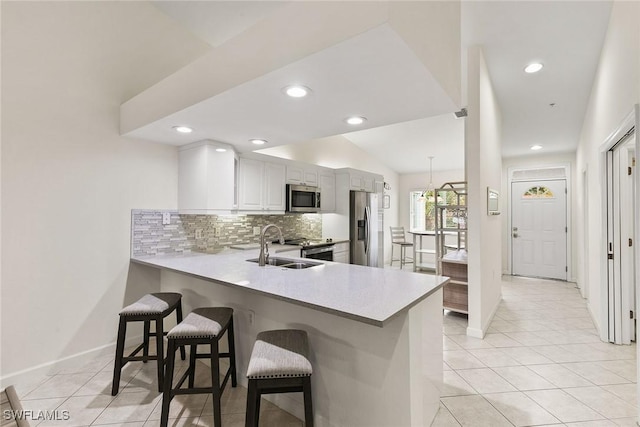 kitchen with a peninsula, white cabinetry, appliances with stainless steel finishes, and a breakfast bar area