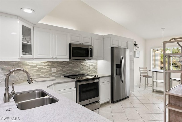 kitchen featuring tasteful backsplash, white cabinets, glass insert cabinets, appliances with stainless steel finishes, and a sink