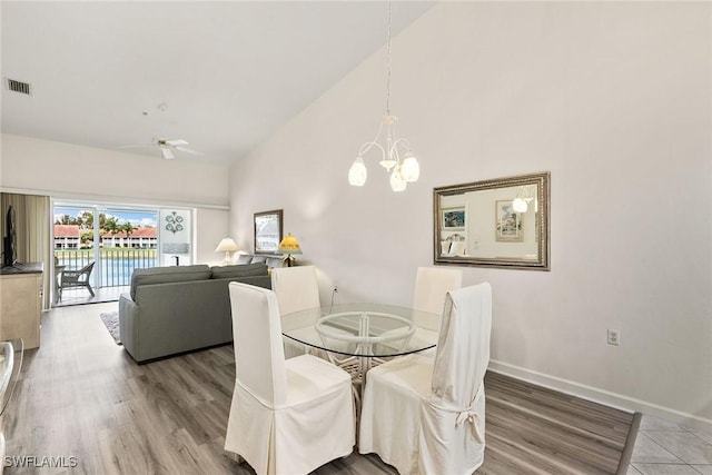 dining space featuring high vaulted ceiling, baseboards, visible vents, and wood finished floors