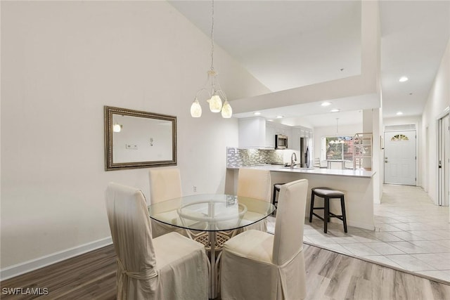 dining area featuring light wood-style floors, recessed lighting, high vaulted ceiling, and baseboards