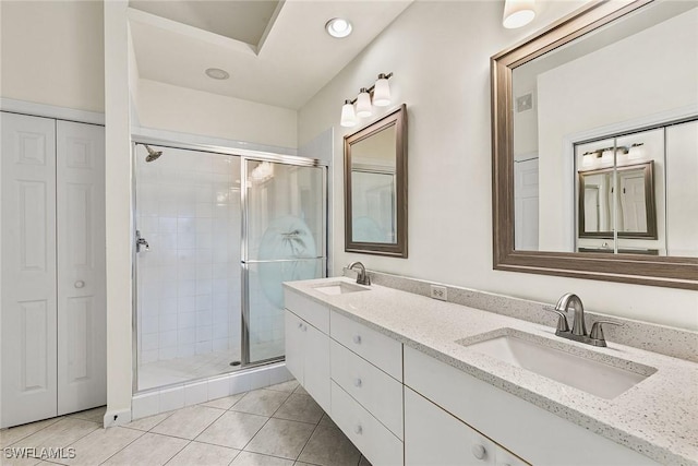 full bathroom with double vanity, a closet, a sink, and a shower stall