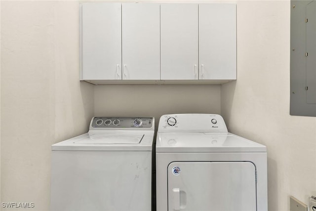 clothes washing area featuring electric panel, cabinet space, and washing machine and clothes dryer