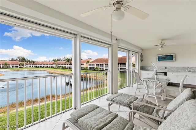 sunroom featuring a water view, a residential view, a ceiling fan, and a sink