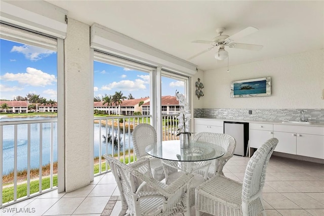 sunroom with a water view, a sink, a residential view, and a ceiling fan