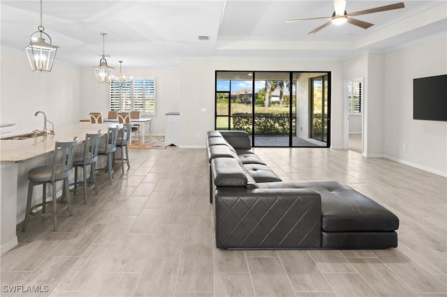 living room featuring baseboards, a tray ceiling, visible vents, and crown molding