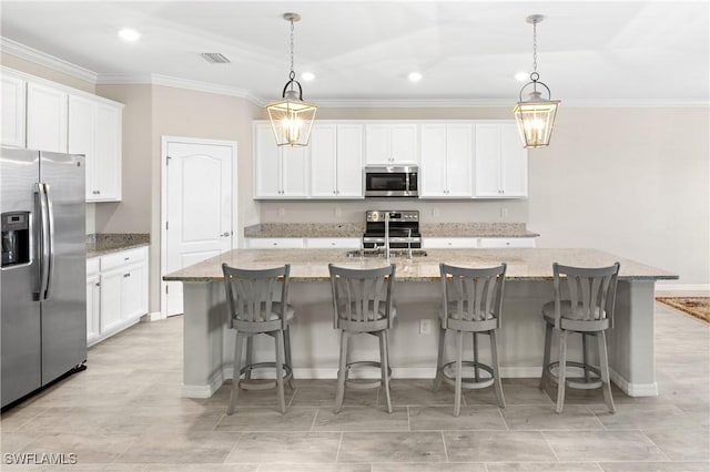 kitchen with visible vents, appliances with stainless steel finishes, a kitchen island with sink, crown molding, and white cabinetry