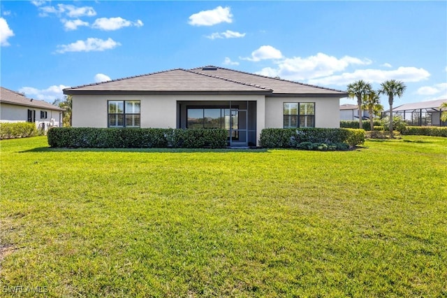 rear view of property featuring a lawn and stucco siding