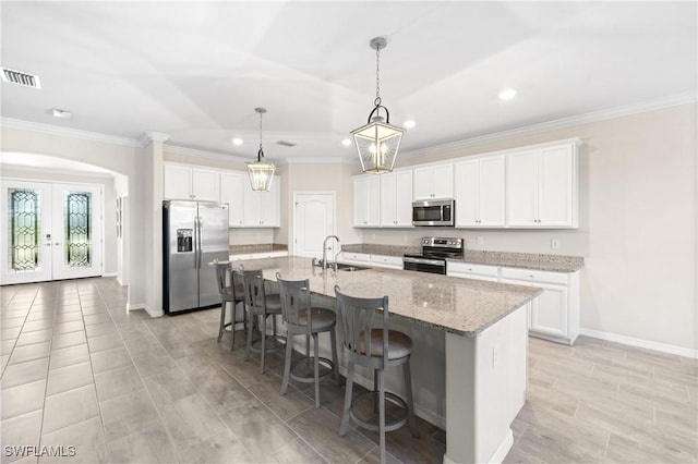 kitchen with a breakfast bar area, a sink, visible vents, white cabinetry, and appliances with stainless steel finishes